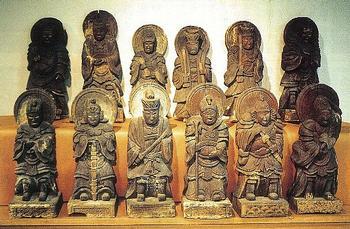刀や杖などをそれぞれ持っている十二体の木像彫刻が6体ずつ段の上に並んでいる写真